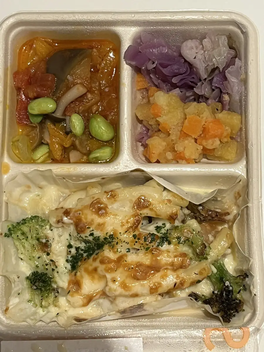 届いたままのシーフードグラタンの容器。表面に焼き色が付いていて、ブロッコリーの一部が焦げている