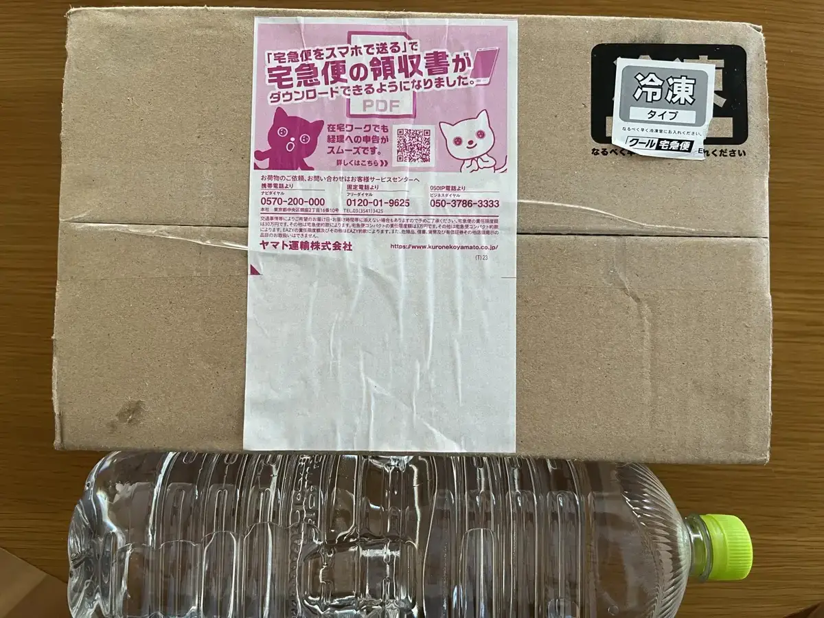 デリピックスのお試しセットの外箱。大きさを比べるペットボトルと並べた写真で、冷凍のシールが貼られている
